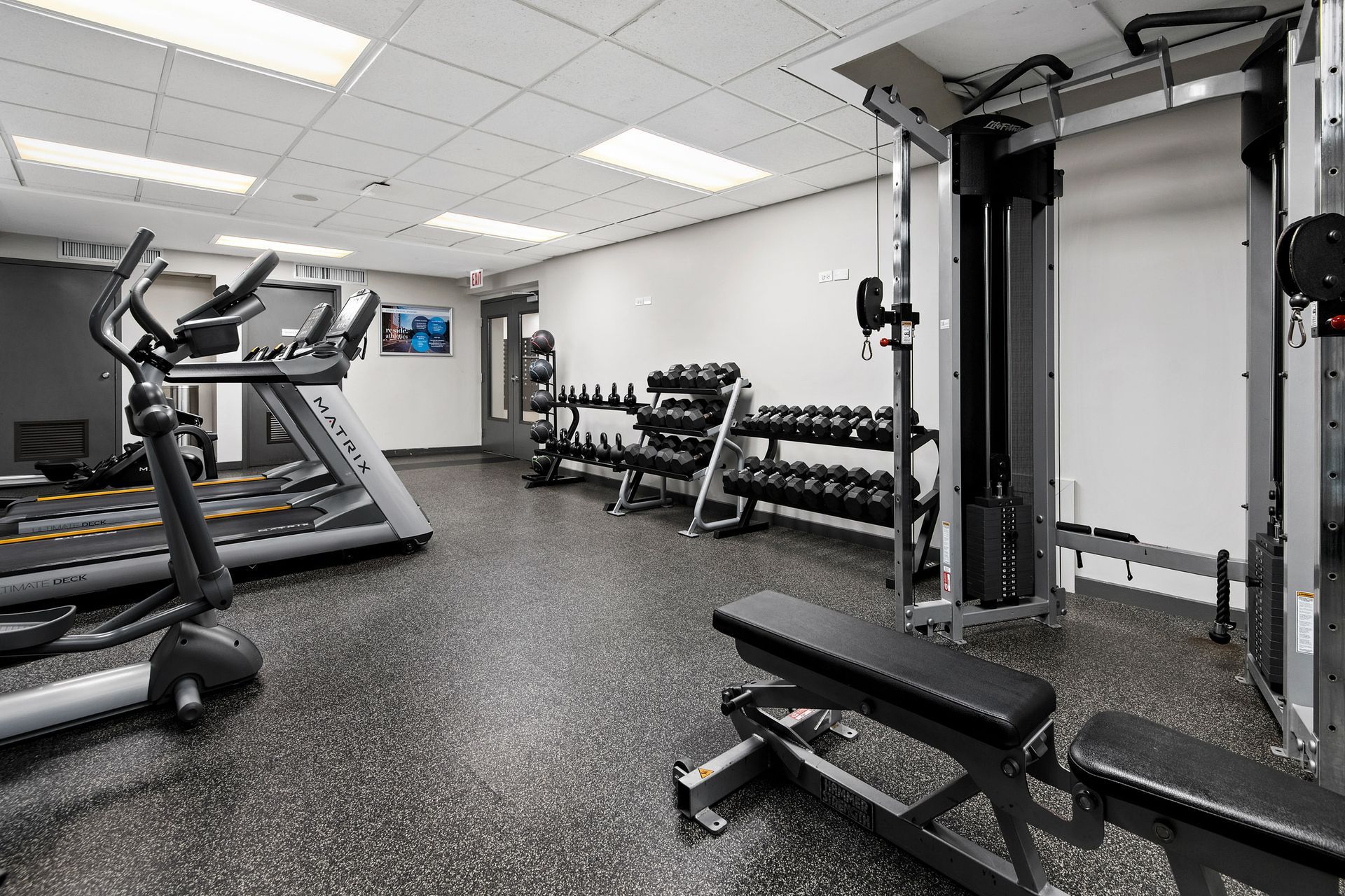 A gym with a treadmill, elliptical, and dumbbells at Reside 707.