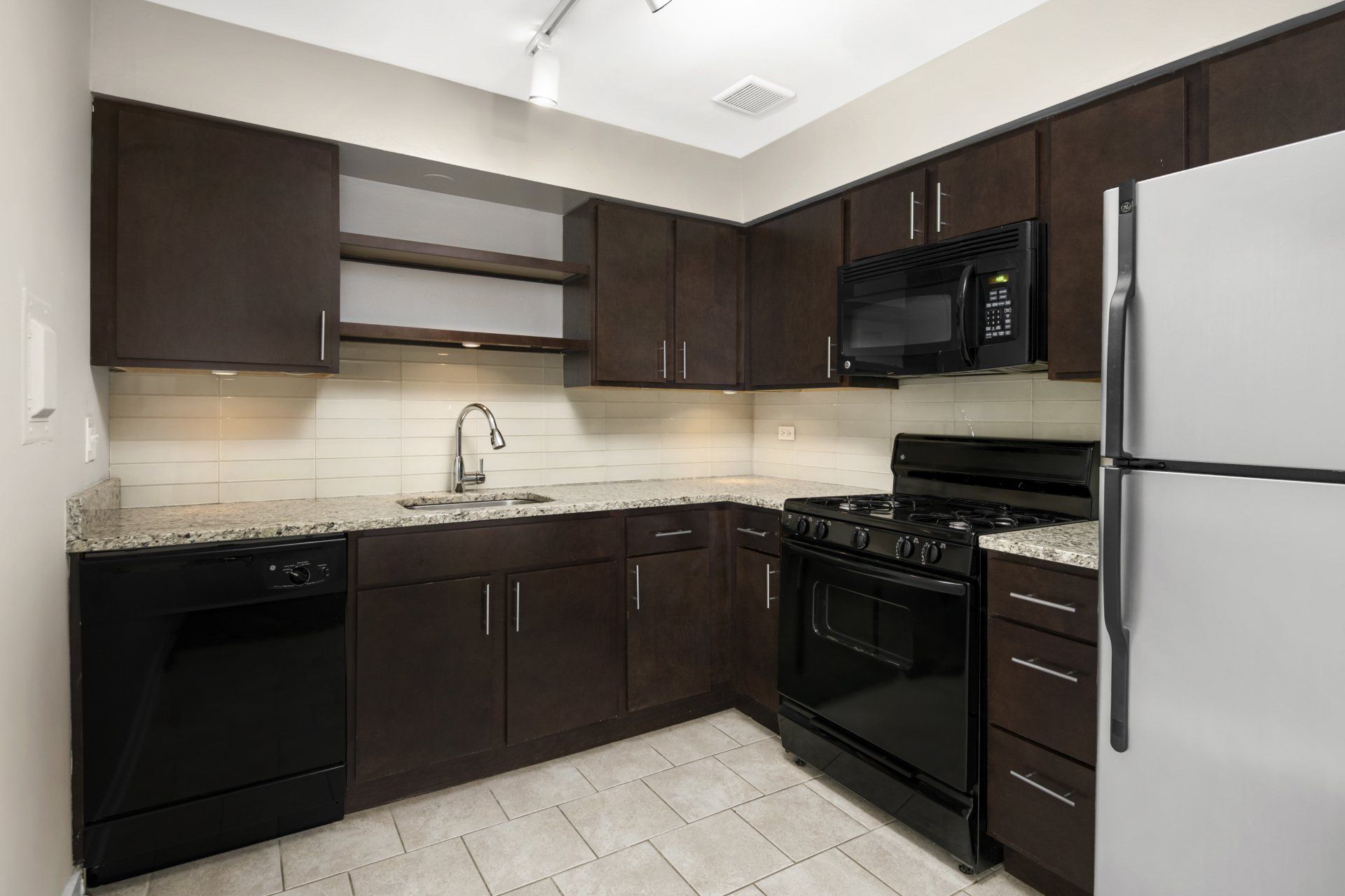 A kitchen with stainless steel appliances and brown cabinets at Reside 707.
