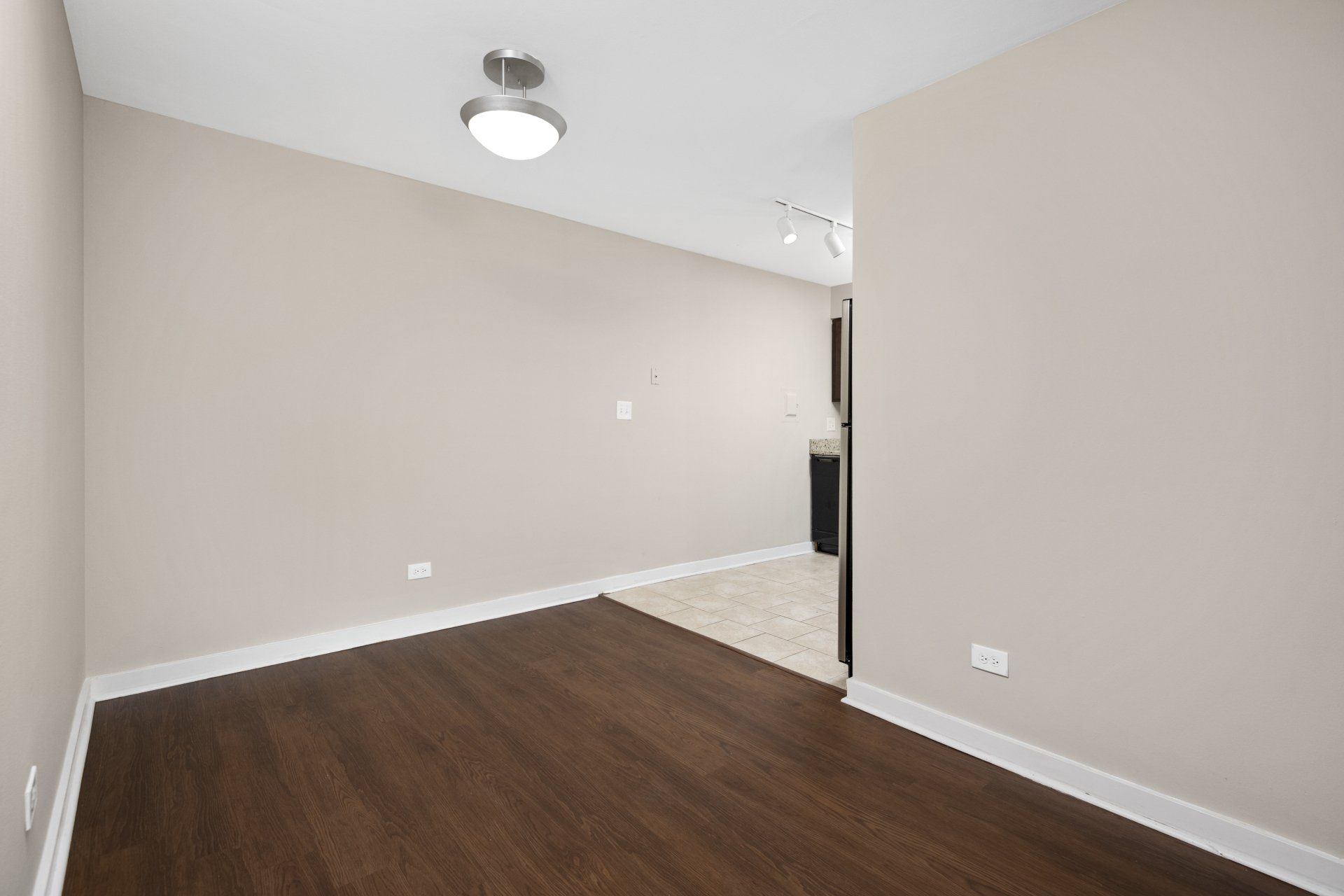 An empty room with hardwood floors and a ceiling fan at Reside 707.