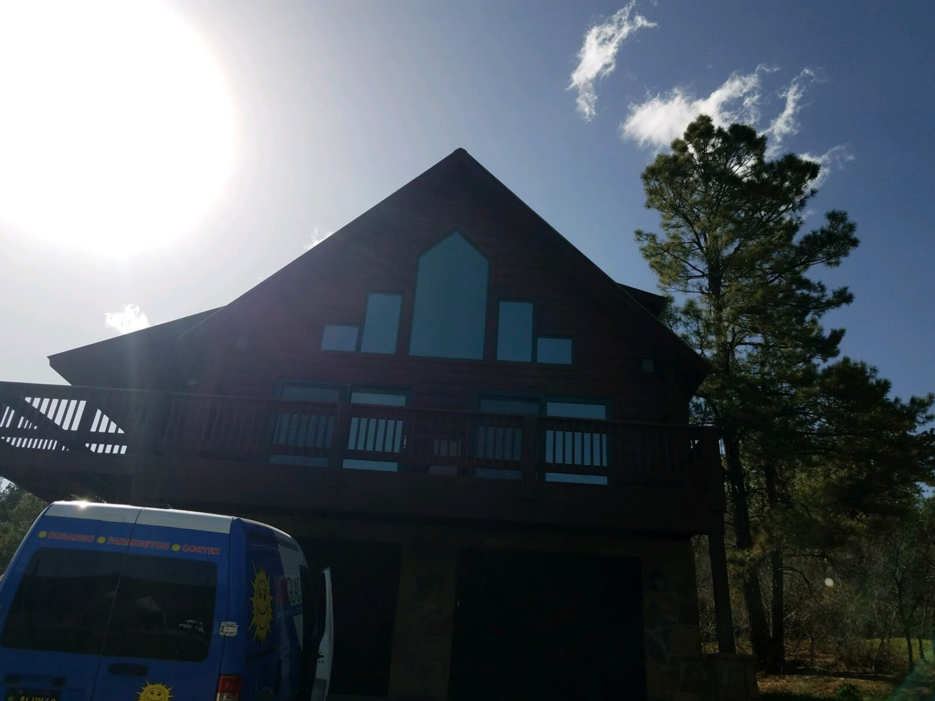 A blue van is parked in front of a large house