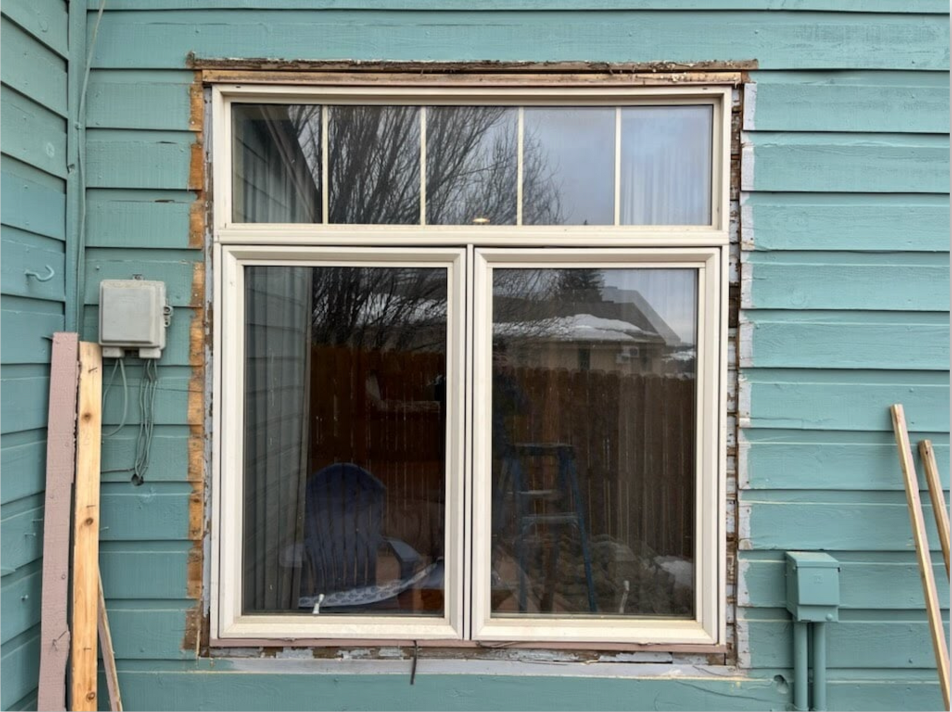 A window is being installed on the side of a house.