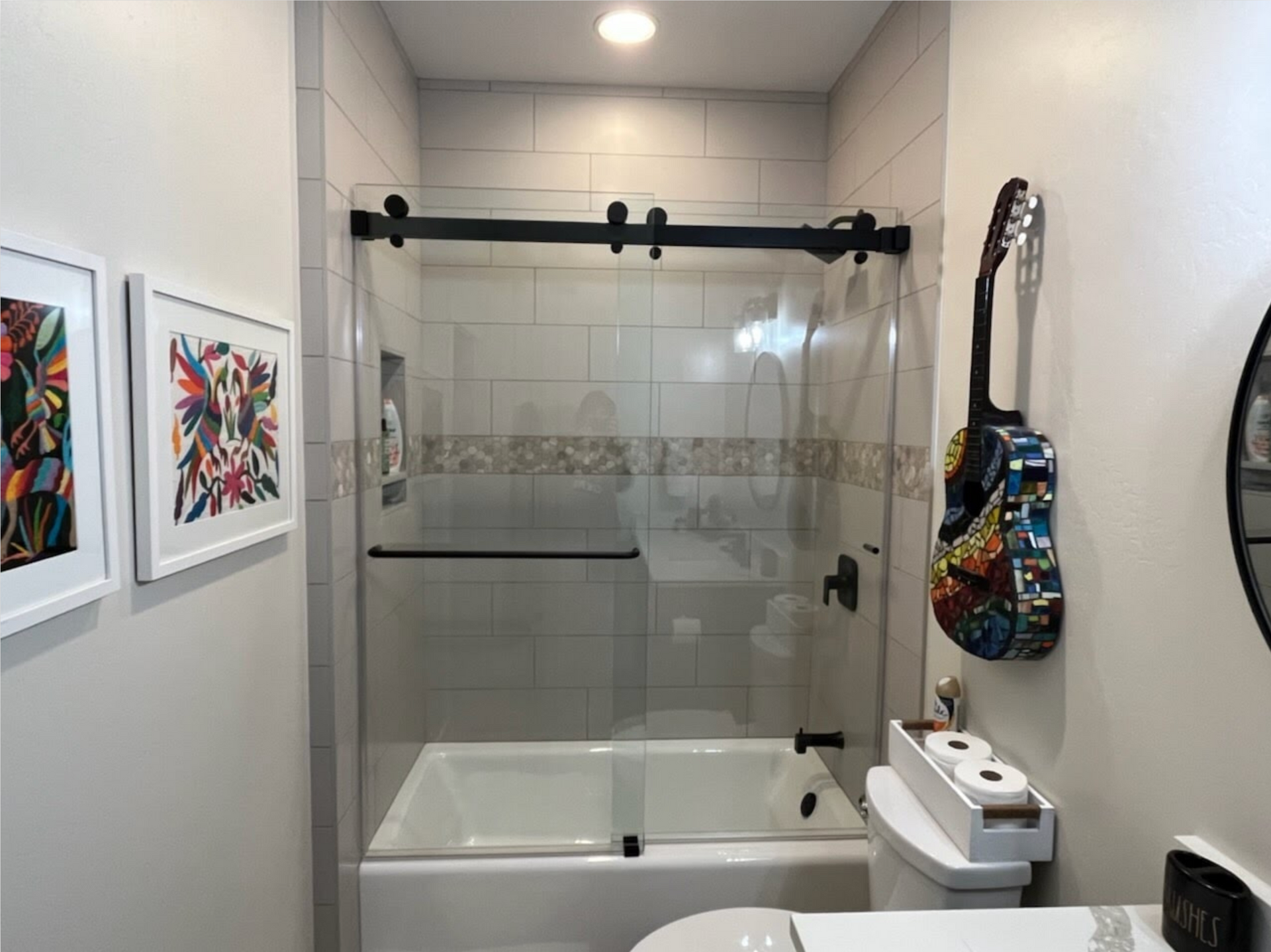 A bathroom with a bathtub , toilet , and sliding glass shower door.