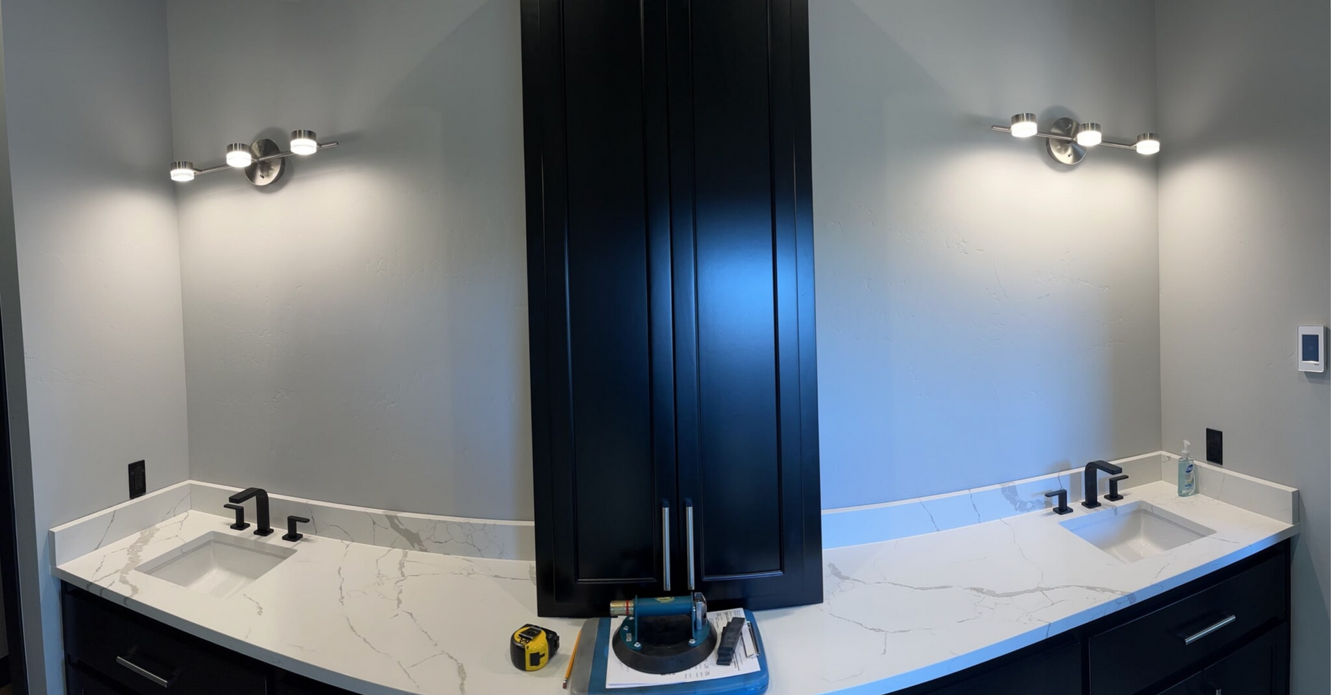 A bathroom with two sinks , a mirror , and black cabinets.