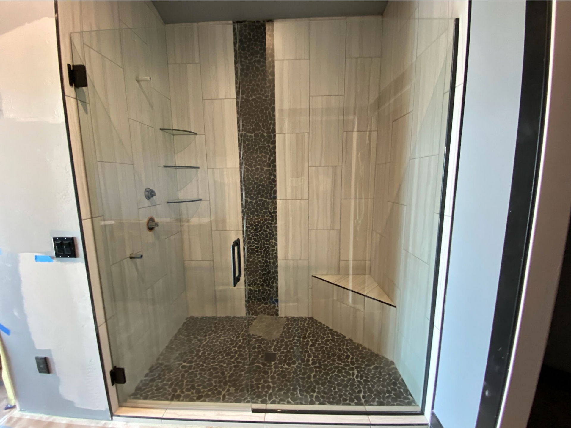 A bathroom with a walk in shower with a glass door.
