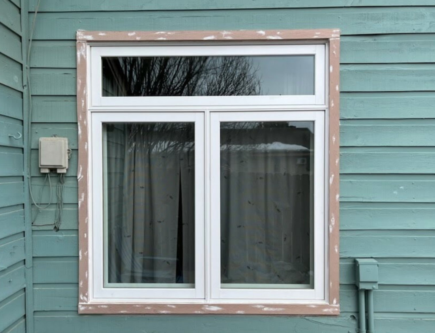 A white window is on the side of a house.
