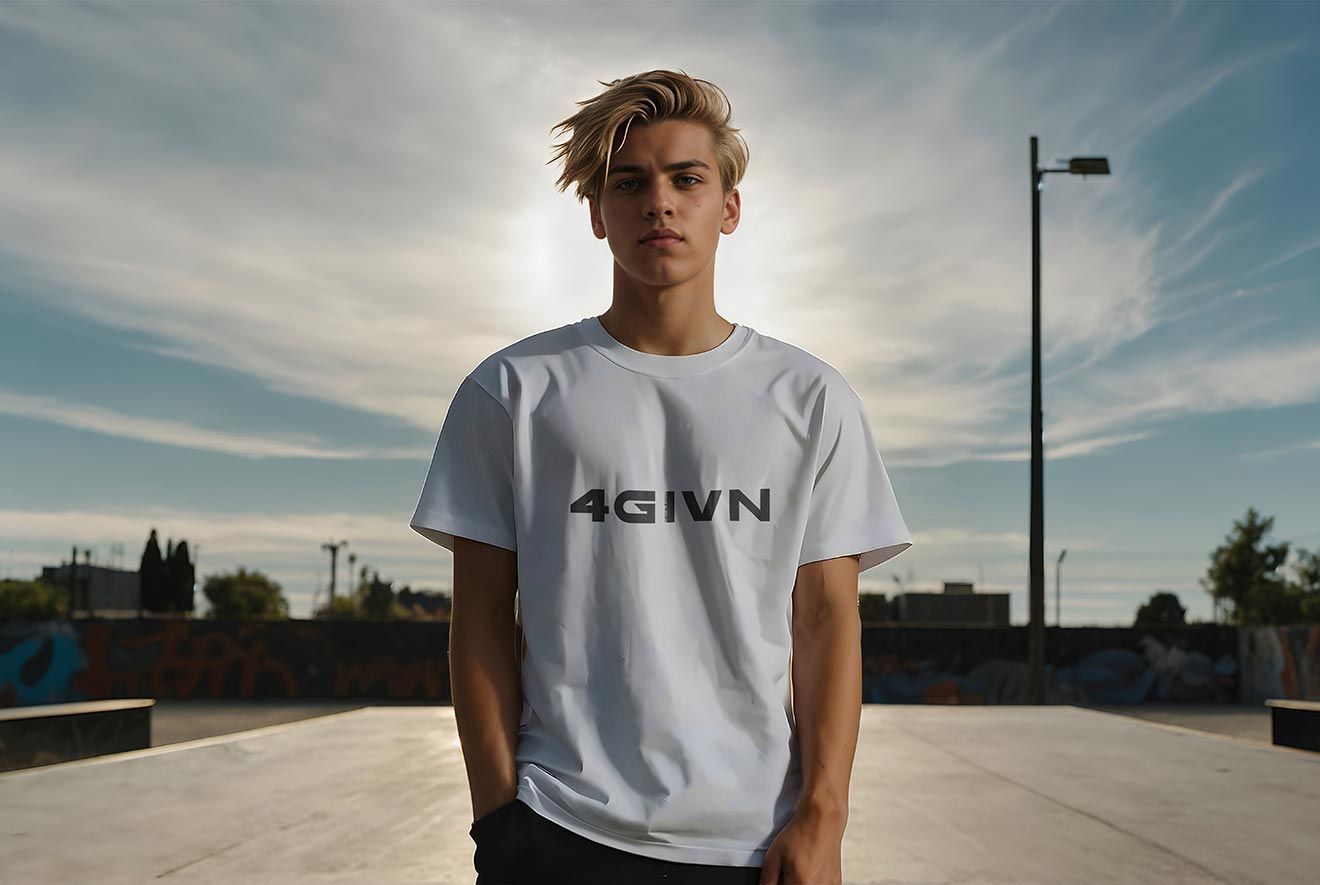 Young person with blonde hair in white t-shirt stands in a skate park with hands in pockets.