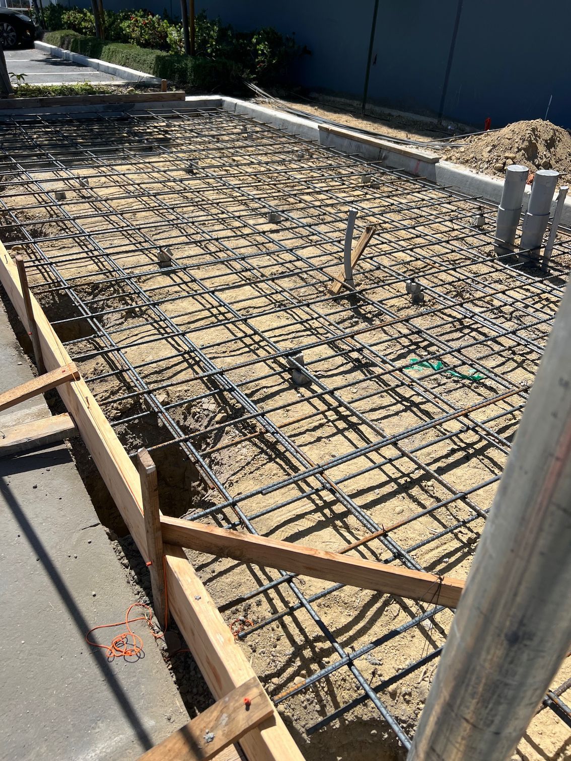 A concrete driveway is being built next to a wooden fence.
