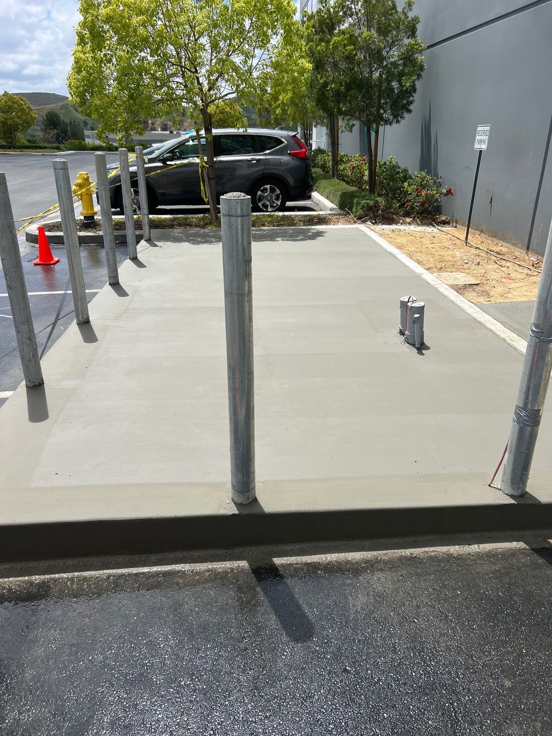 A car is parked in a parking lot next to a concrete walkway.