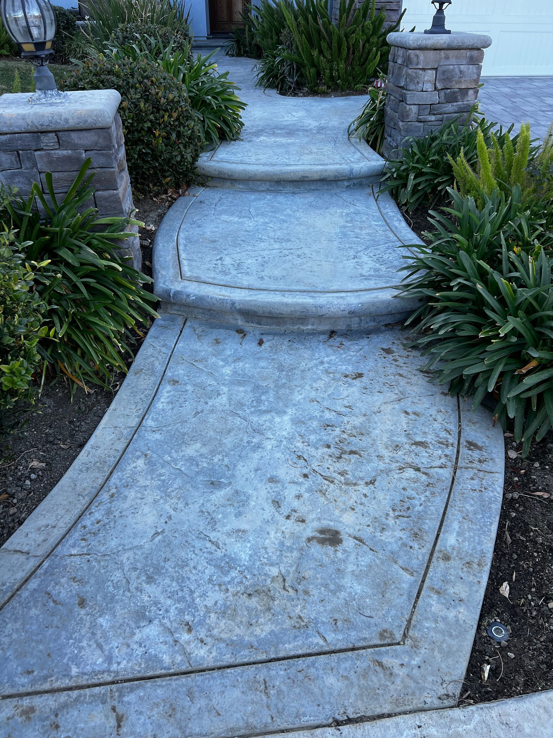 A concrete walkway with steps leading up to a house.