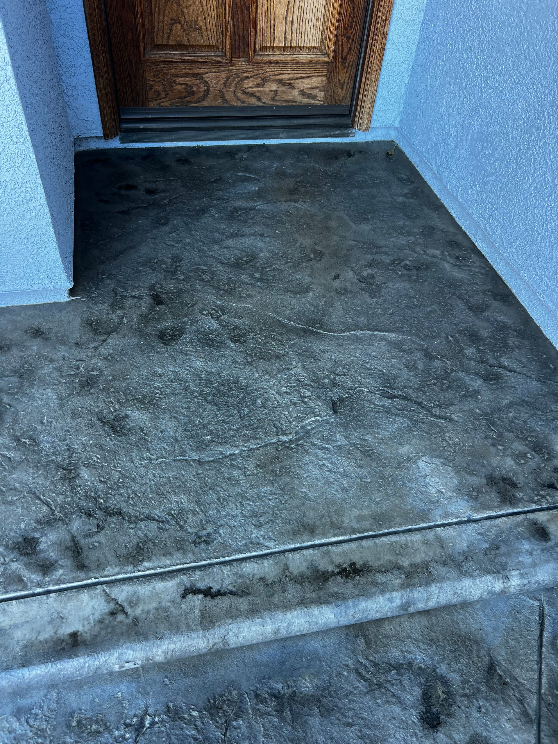 A concrete porch with steps leading up to a door.