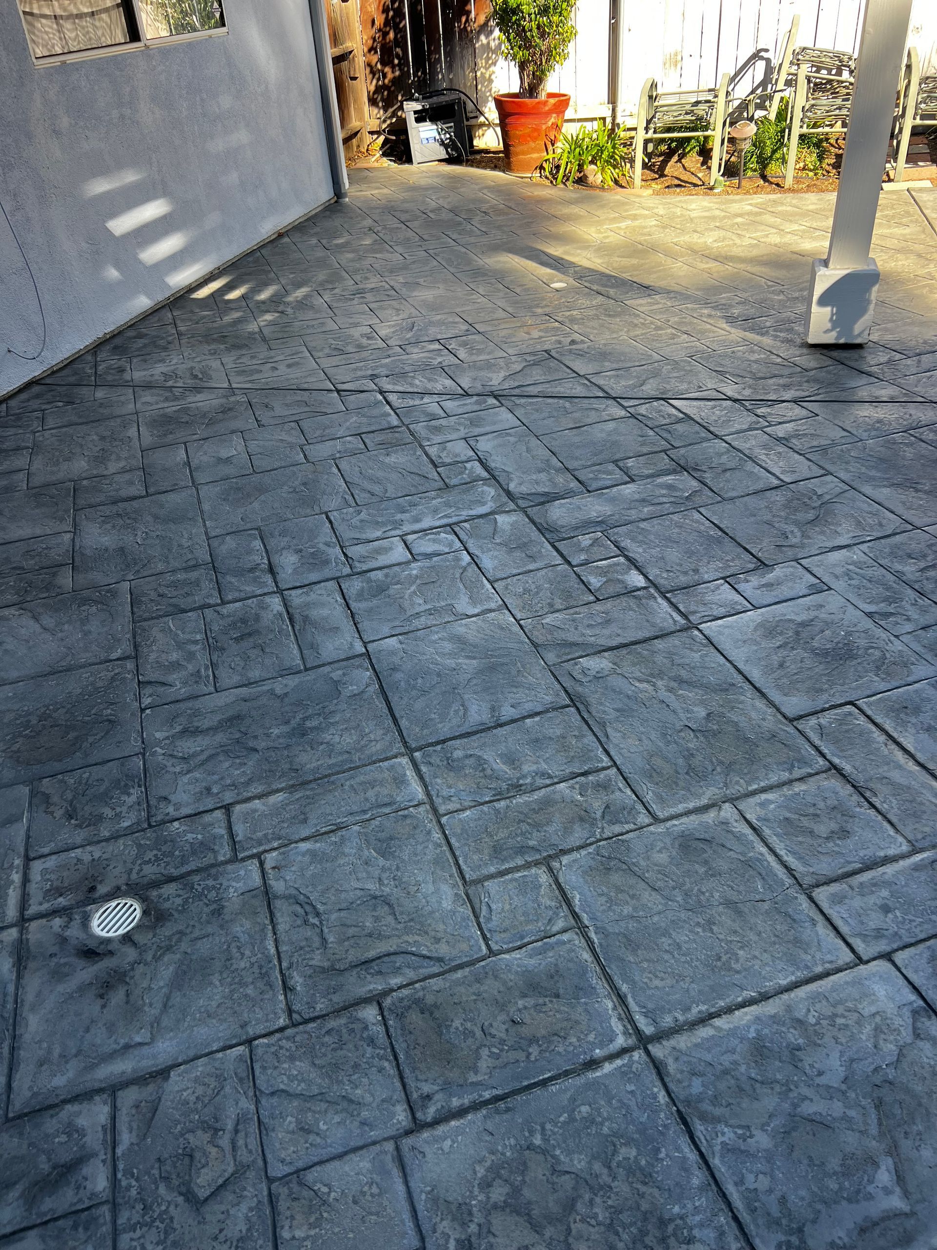 A patio with a concrete floor and a fence in the background.