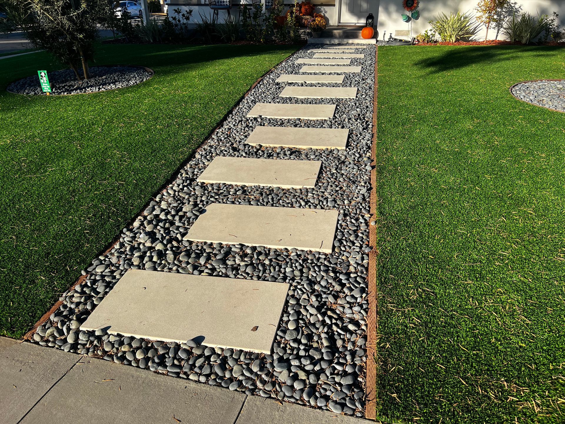 A walkway with stepping stones and gravel leading to a house.