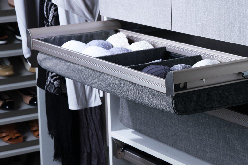 A drawer in a closet with clothes in it