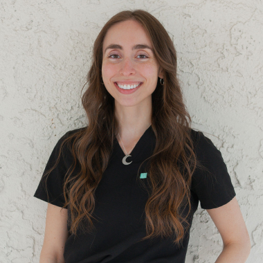 A woman wearing a black scrub top is smiling for the camera