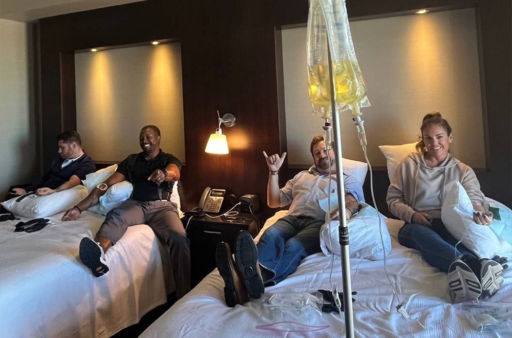 IV hydration treatment session with four people relaxing in a hotel room