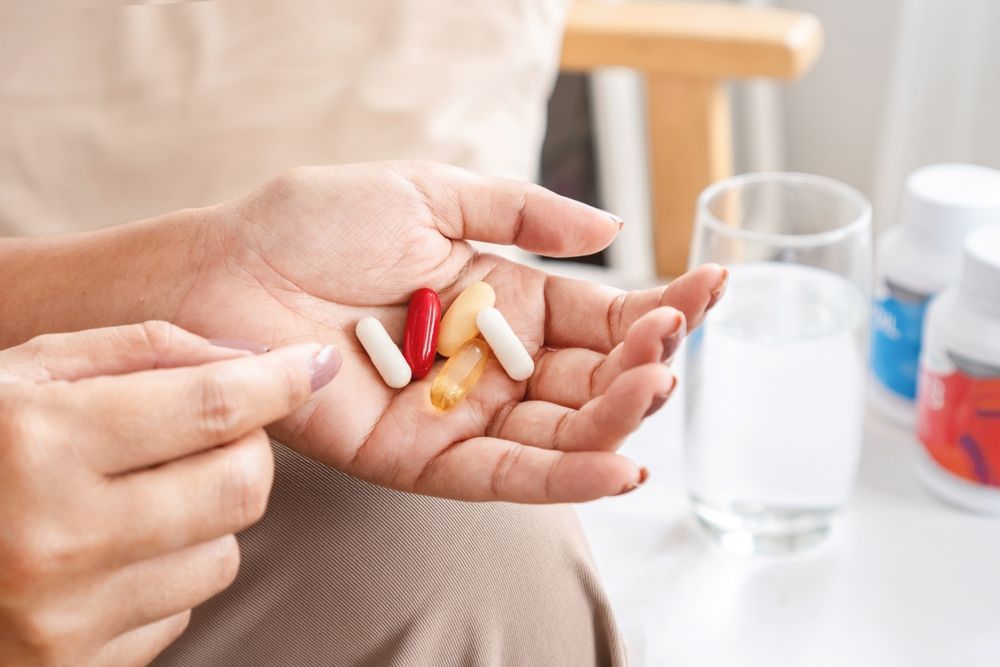 A woman is holding a handful of pills in her hand.