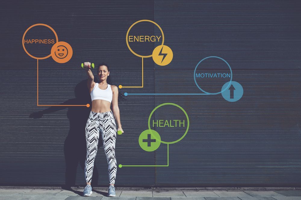 A woman is standing in front of a wall holding a dumbbell.