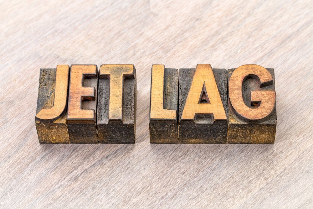 The word jet lag is written in wooden letterpress type on a wooden table.