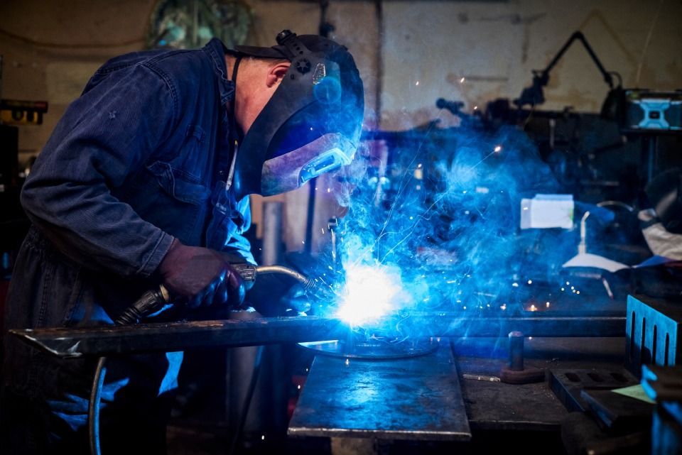 A man is welding a piece of metal in a factory.