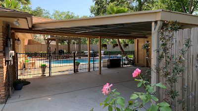 Backyard with a pool, patio, and rose bushes. A covered patio area with a pool view.