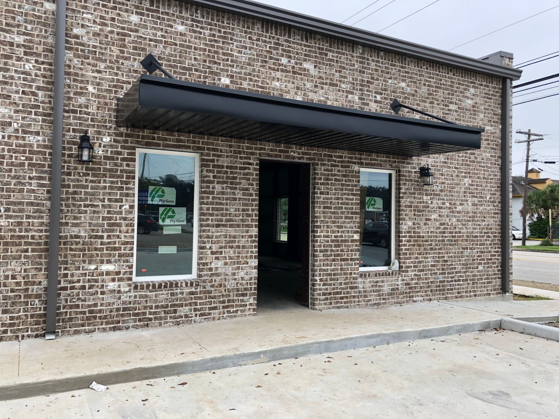 Brick building exterior with black awning, windows, and open door.