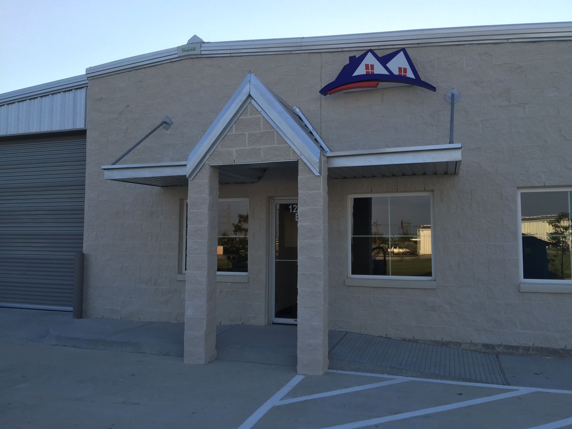 Exterior of a building with a blue, red, and white roof logo above the entrance.