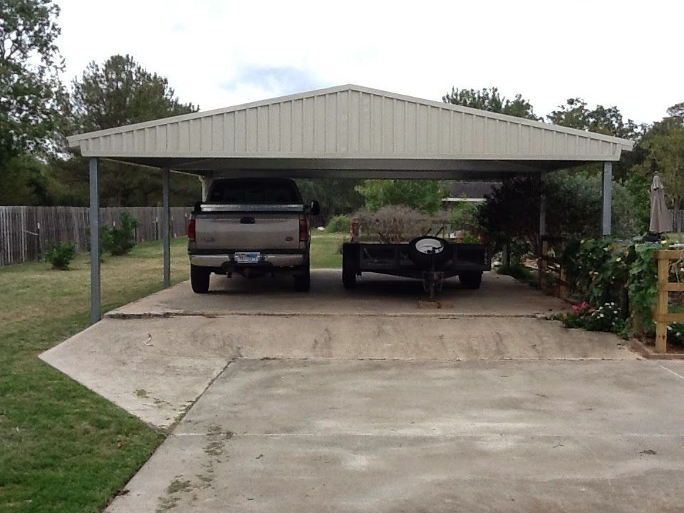 Tan metal carport sheltering a pickup truck and a trailer on a concrete driveway.