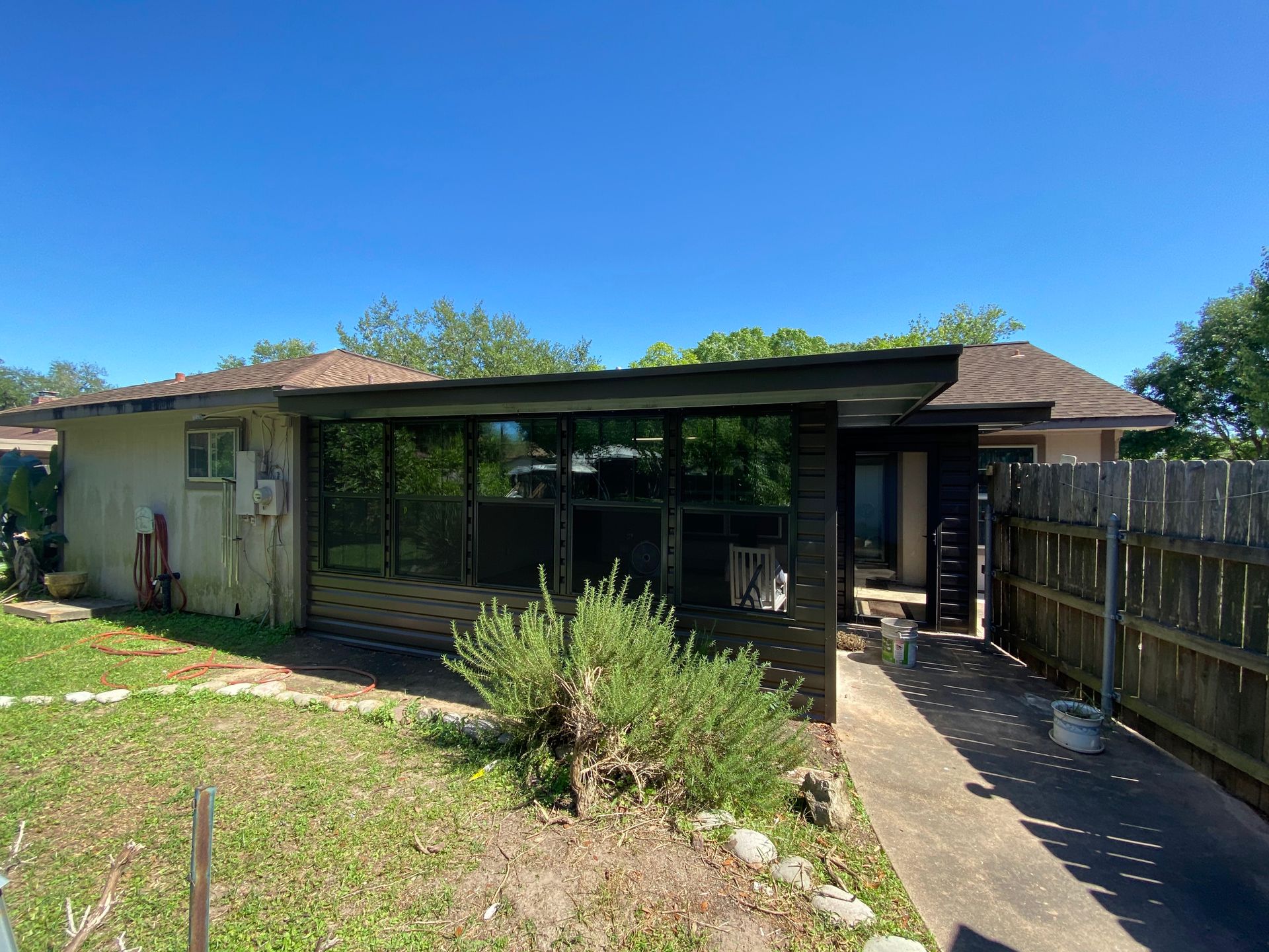 Exterior of a house with a screened porch, on a sunny day.