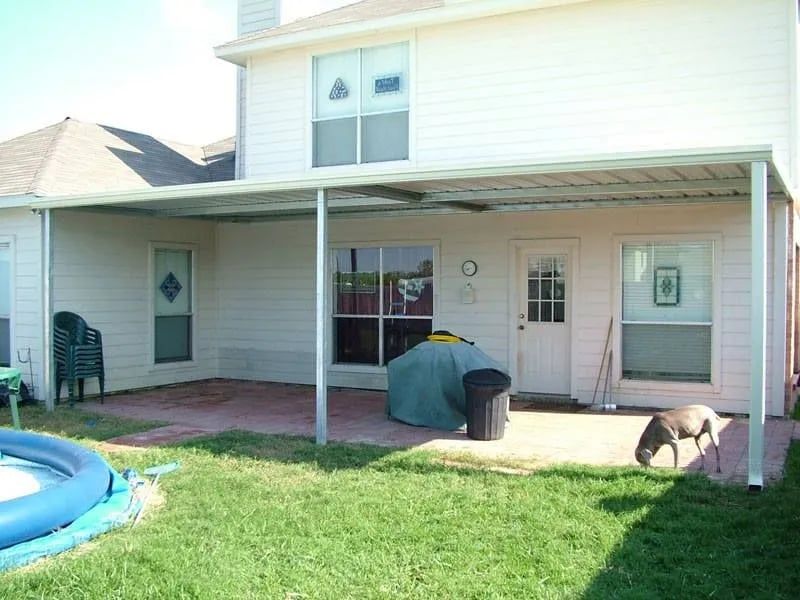 Backyard with patio and covered area; dog, above-ground pool, and green grass.