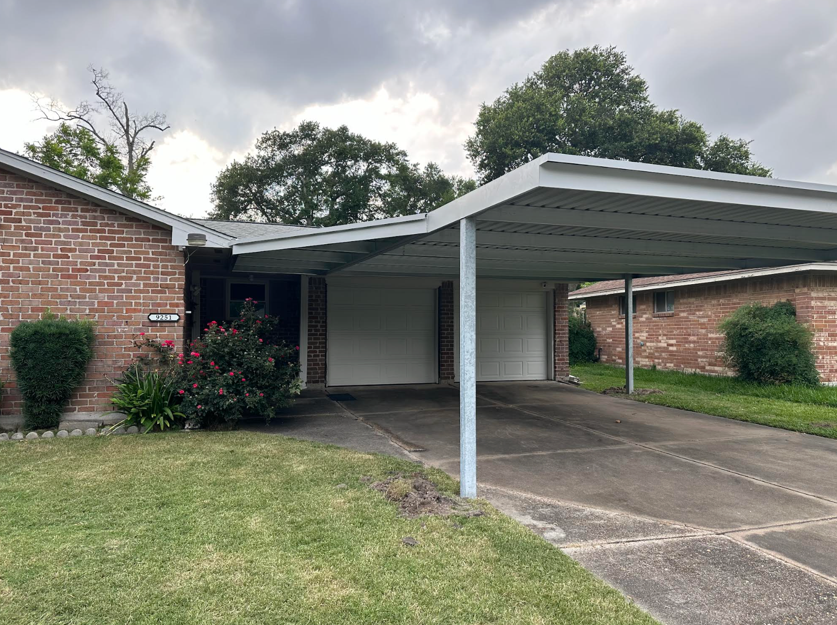 Three bright light bulbs illuminate a brick wall under a dark metal structure.