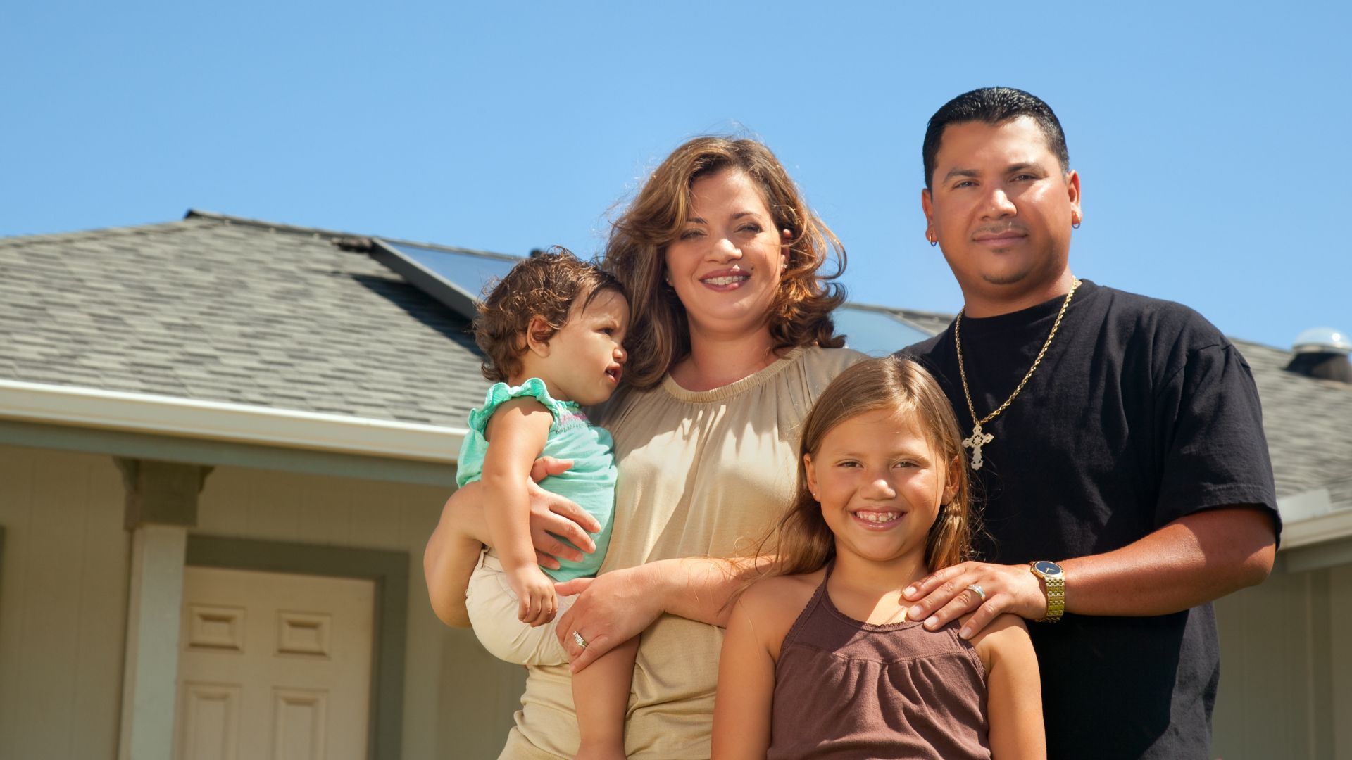 A family is posing for a picture in front of their house.