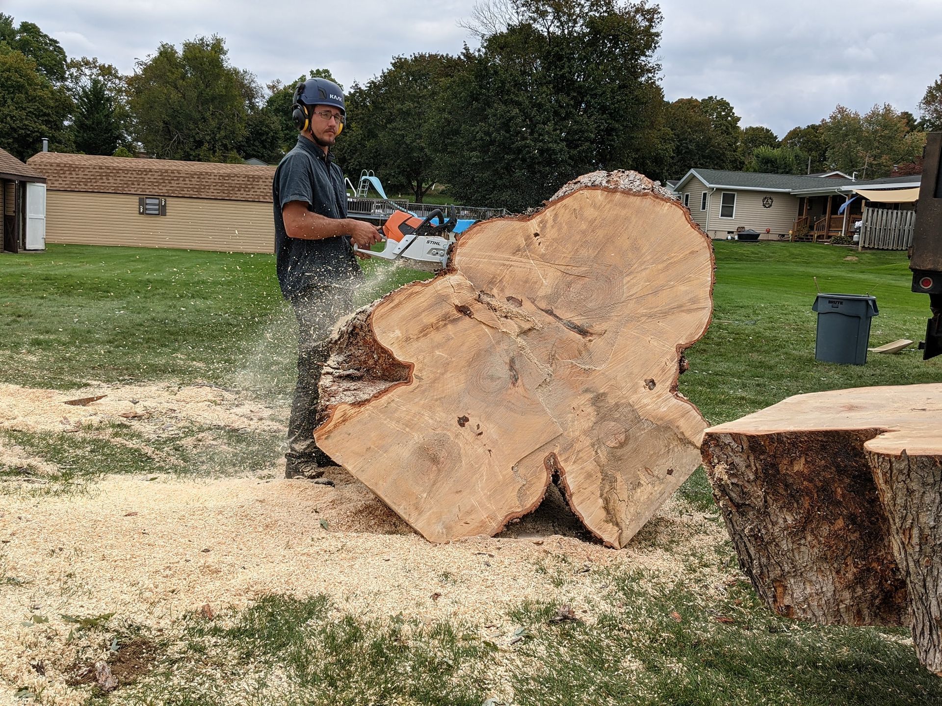 A man is cutting a large piece of wood with a chainsaw.