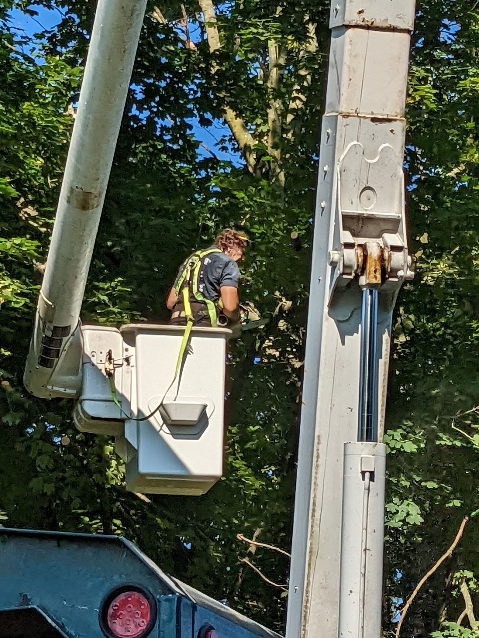 A man is sitting in a bucket on top of a crane.