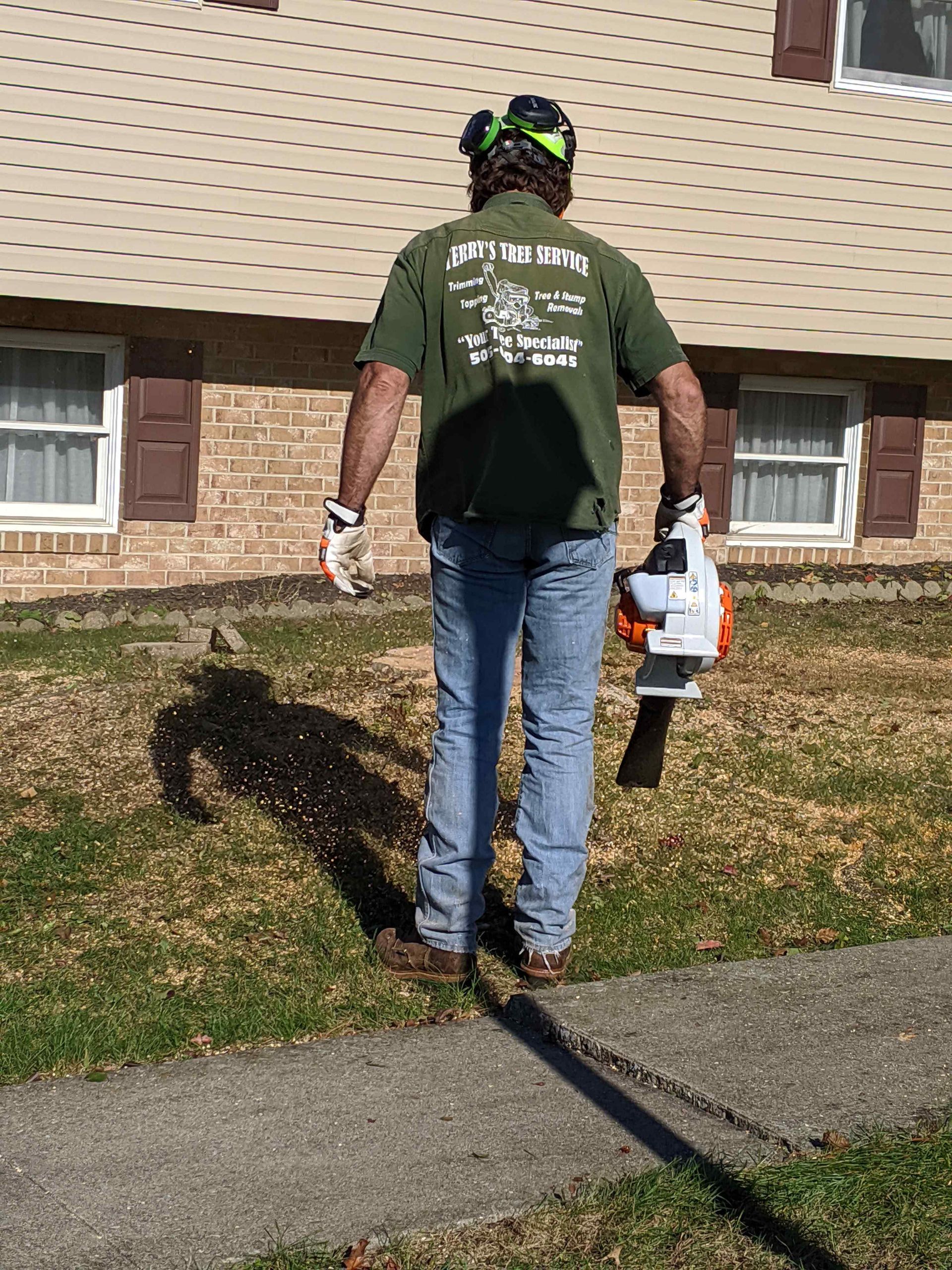 A man is standing in front of a house holding a lawn mower.