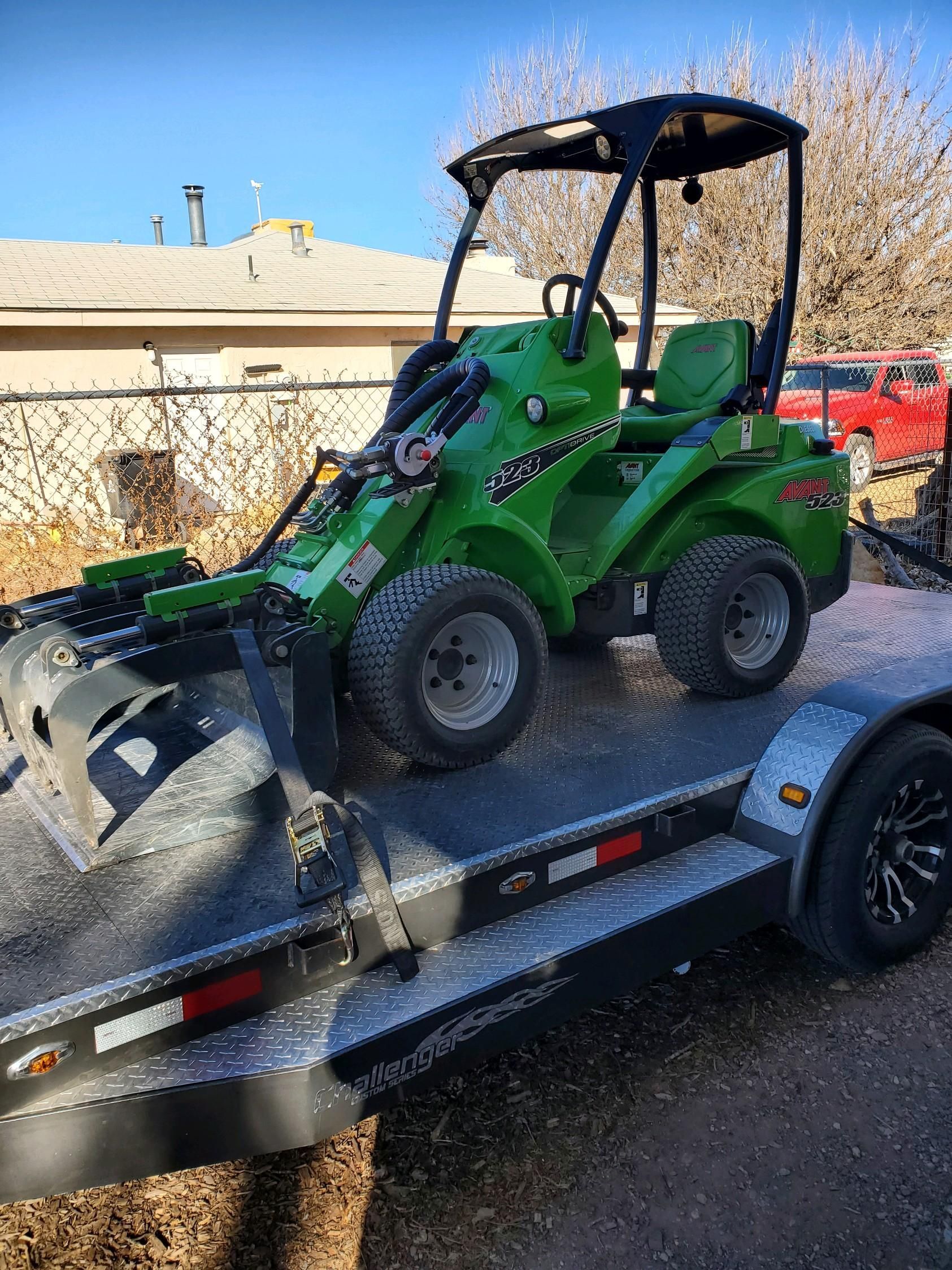 A green tractor is sitting on top of a trailer.
