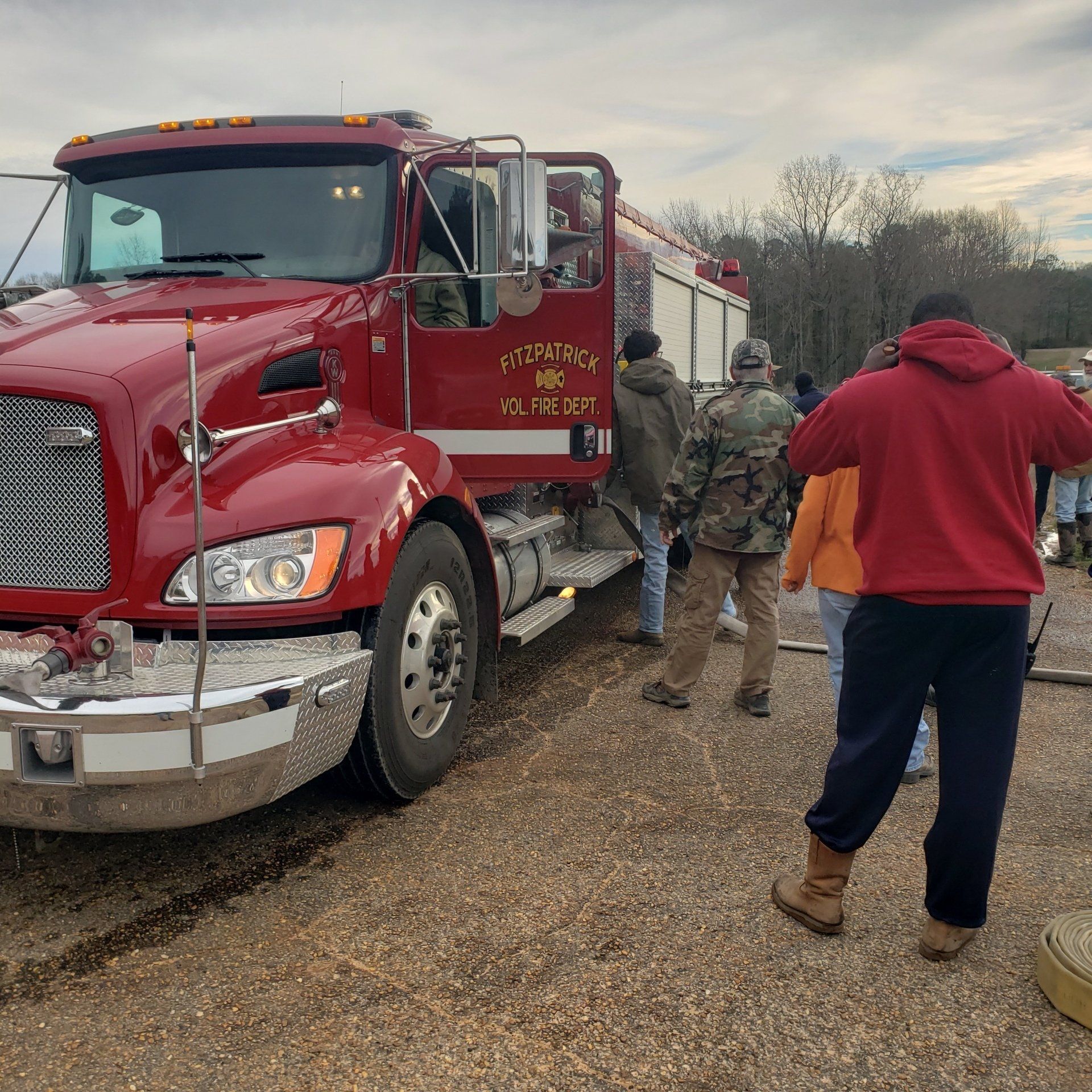 A group of people are standing around a red truck that says nk on the side