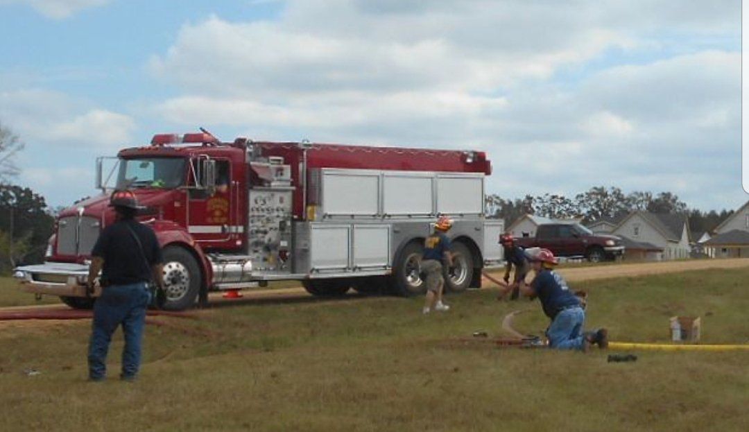 A fire truck is parked in the middle of a field
