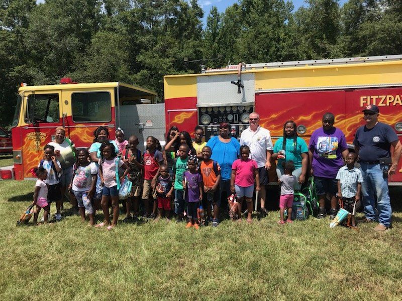 A group of people are posing for a picture in front of a fire truck.