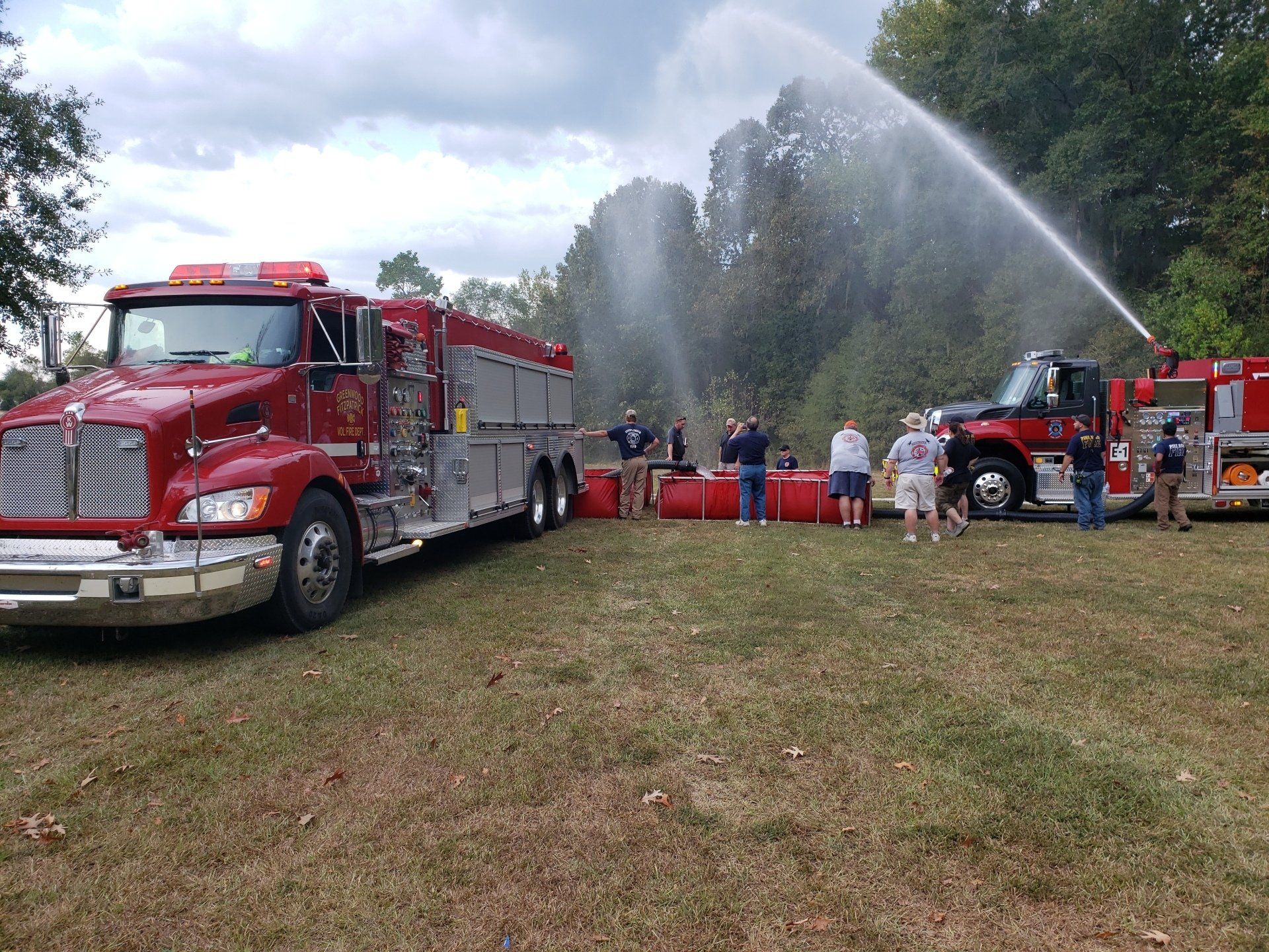 A fire truck is spraying water on a fire in a field.