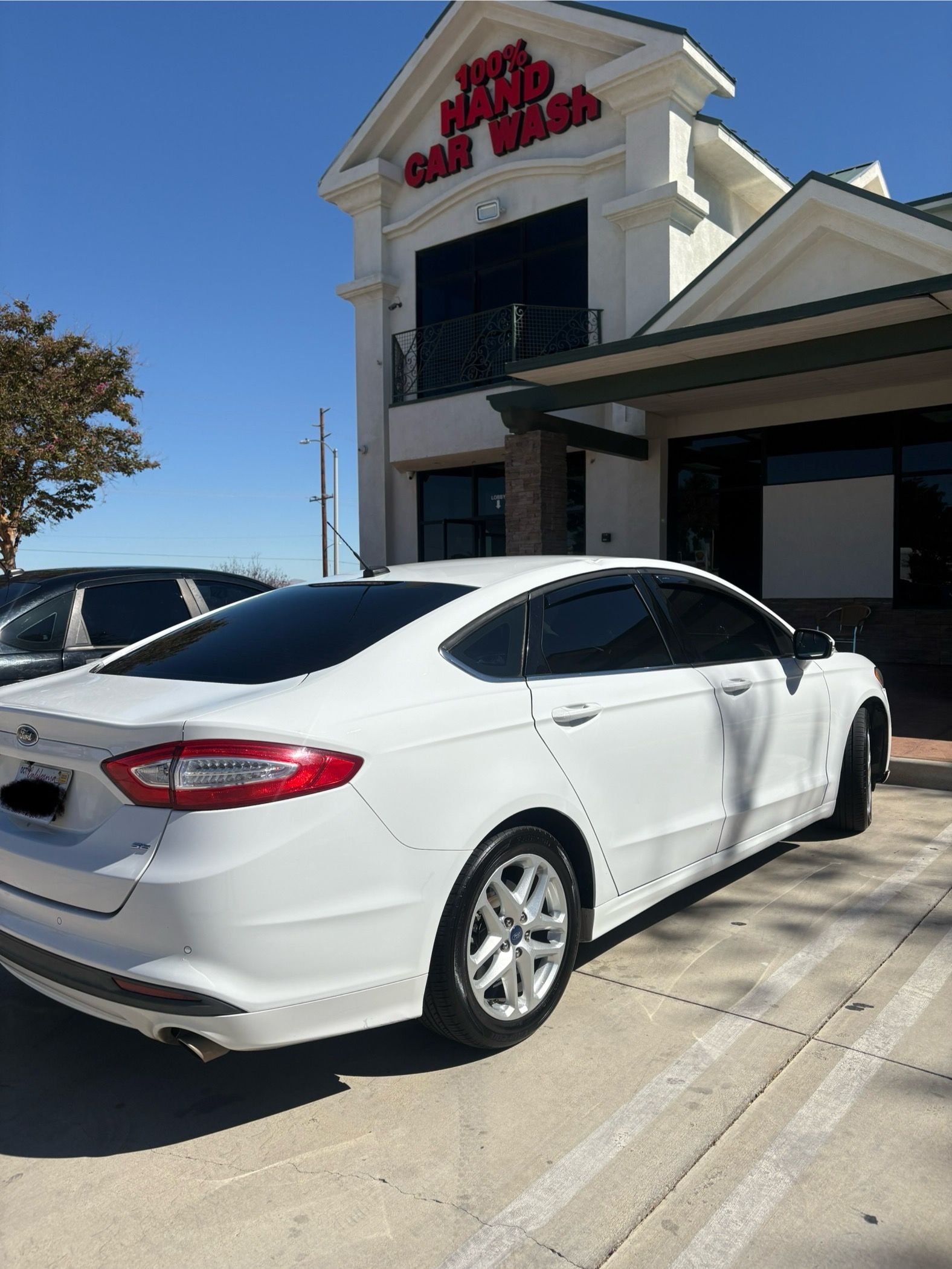 White sedan parked outside a Red Robin restaurant on a sunny day.