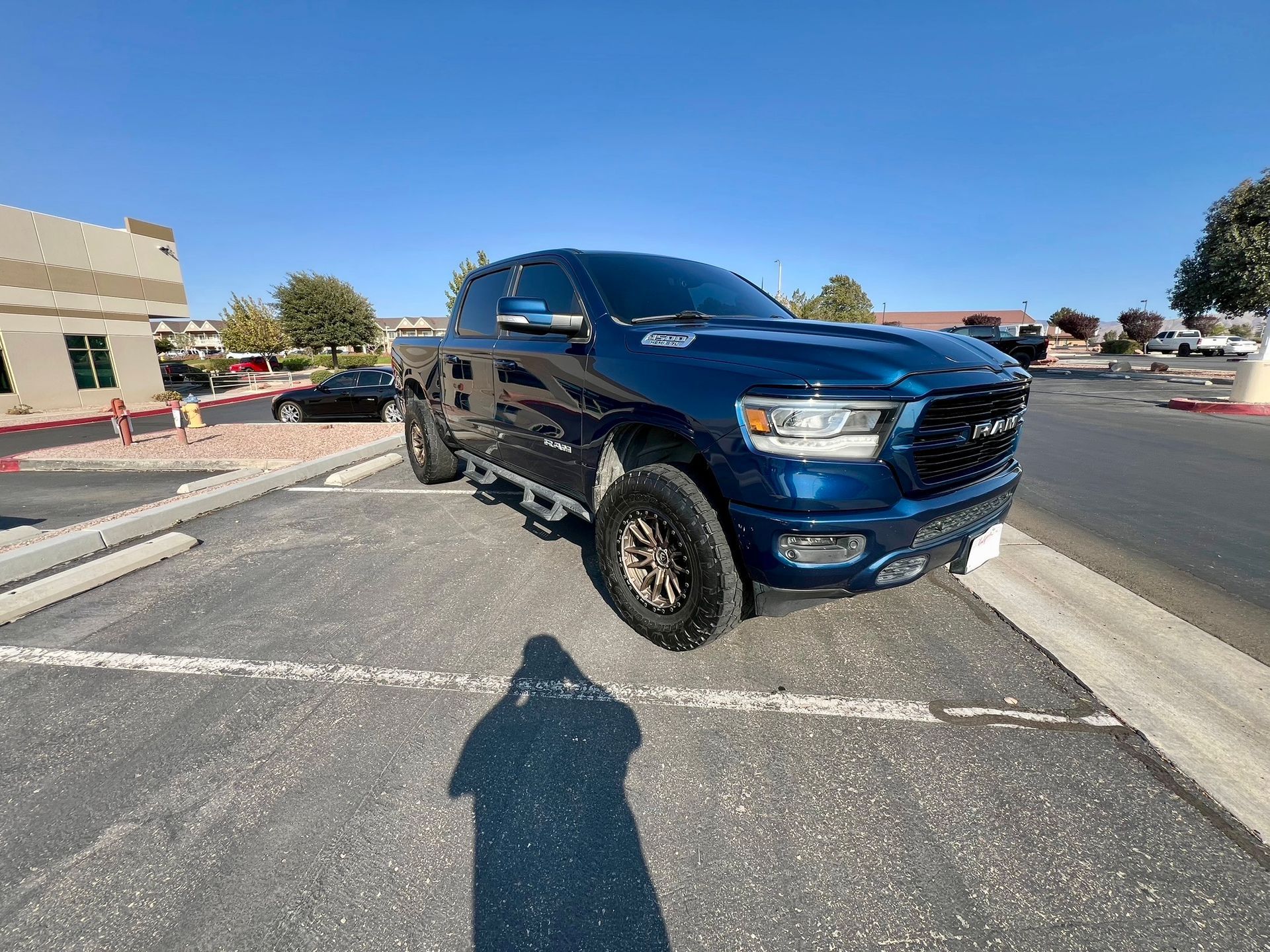 Blue pickup truck parked in a shopping center lot on a sunny day.