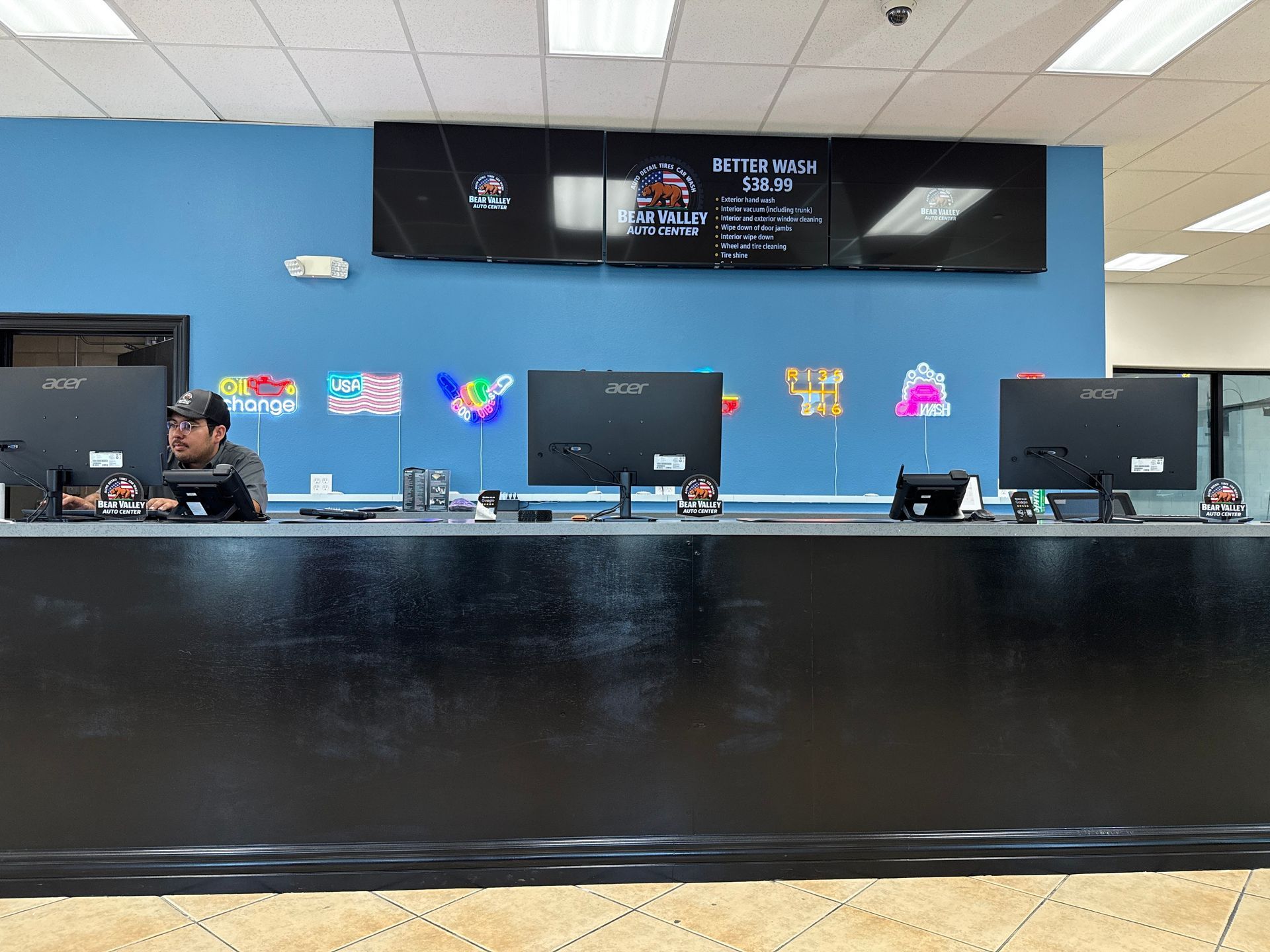 Lobby reception desk with black counter, computer monitors, blue wall, and staff member at left