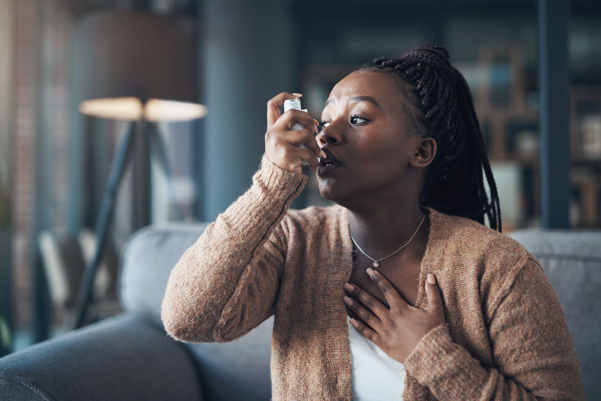 A woman, who needs severe asthma treatment this summer, uses an inhaler to ease her symptoms.