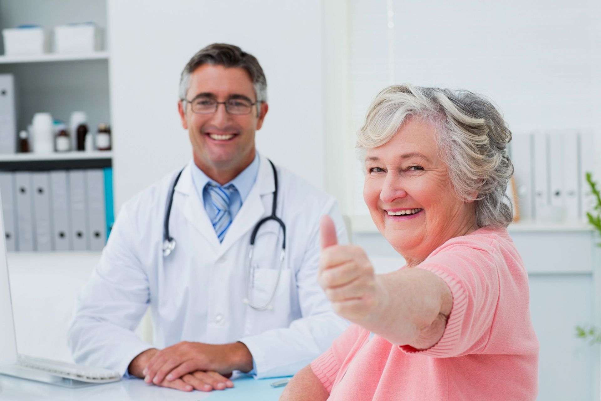 Doctor and patient smiling in office; patient gives thumbs-up.
