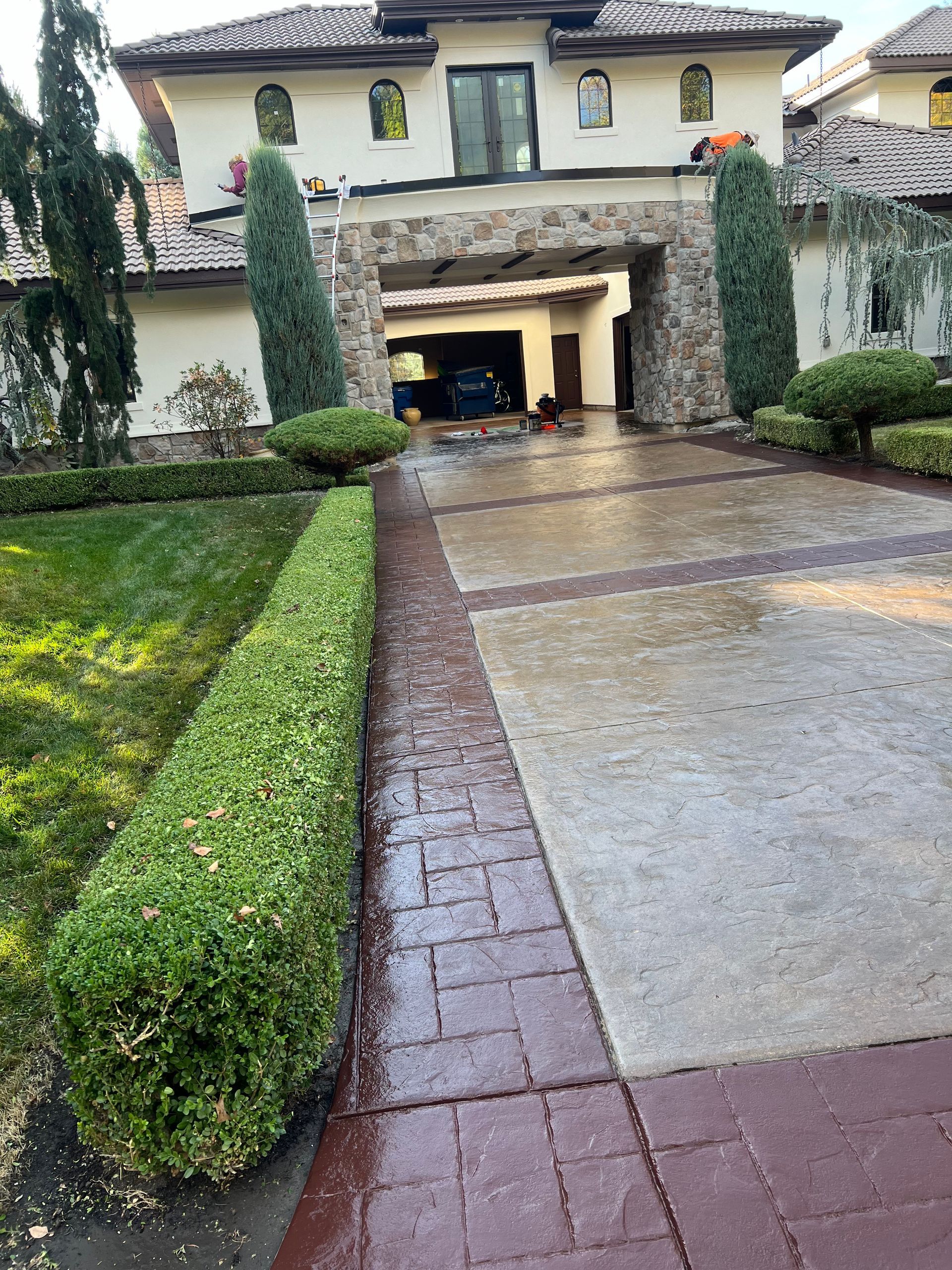 A man is cleaning a concrete driveway with a broom.