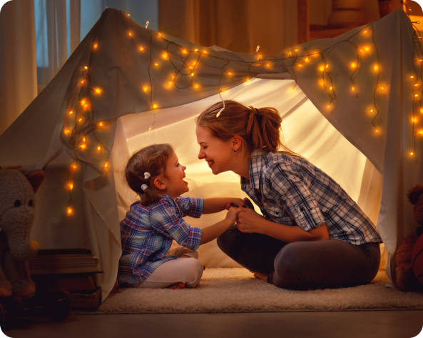 A mother and daughter are playing in a tent with lights.
