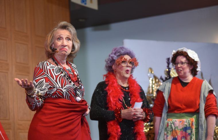 Three women dressed in costumes are standing next to each other on a stage.