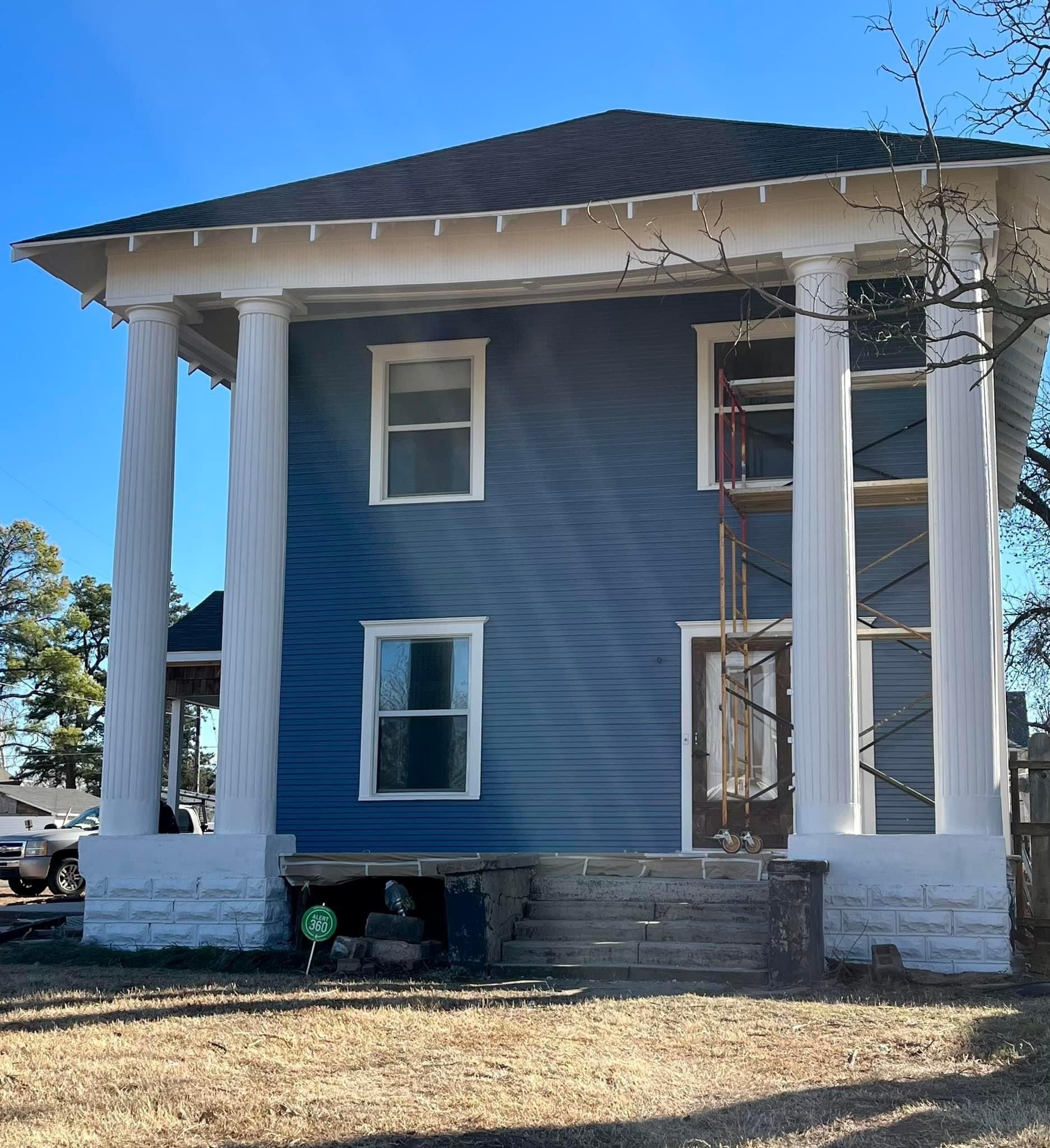 A blue house with white columns and a blue sky in the background