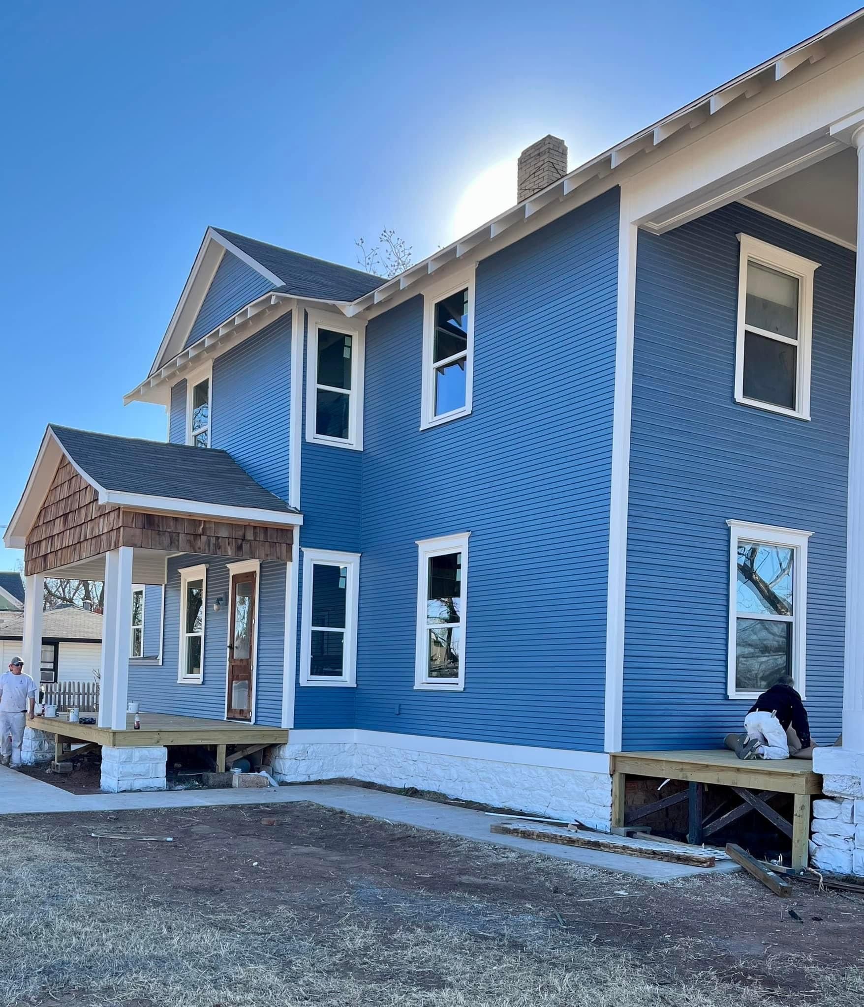 A blue house with white trim is being painted