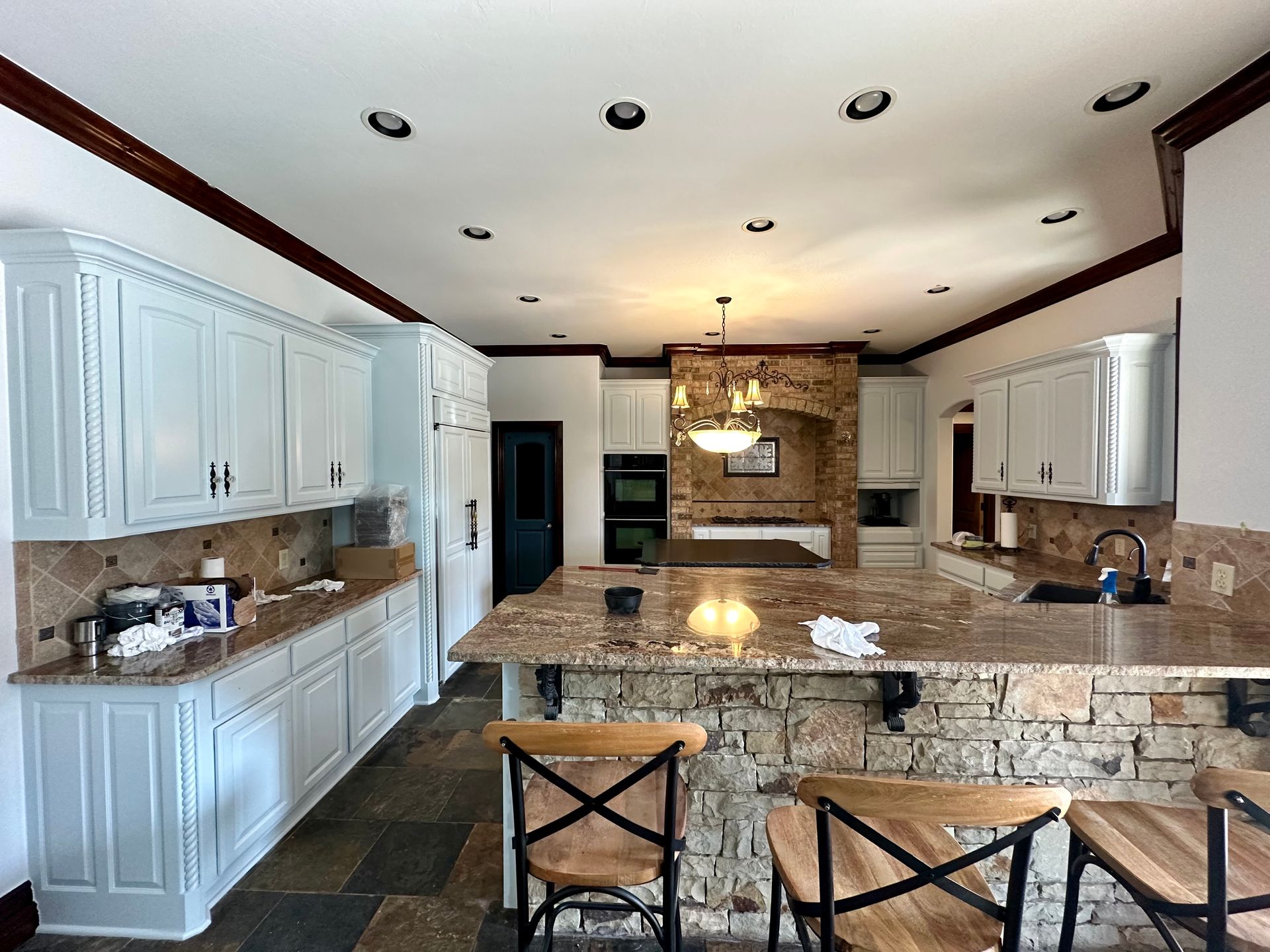 A kitchen with white cabinets , granite counter tops , and a large island.
